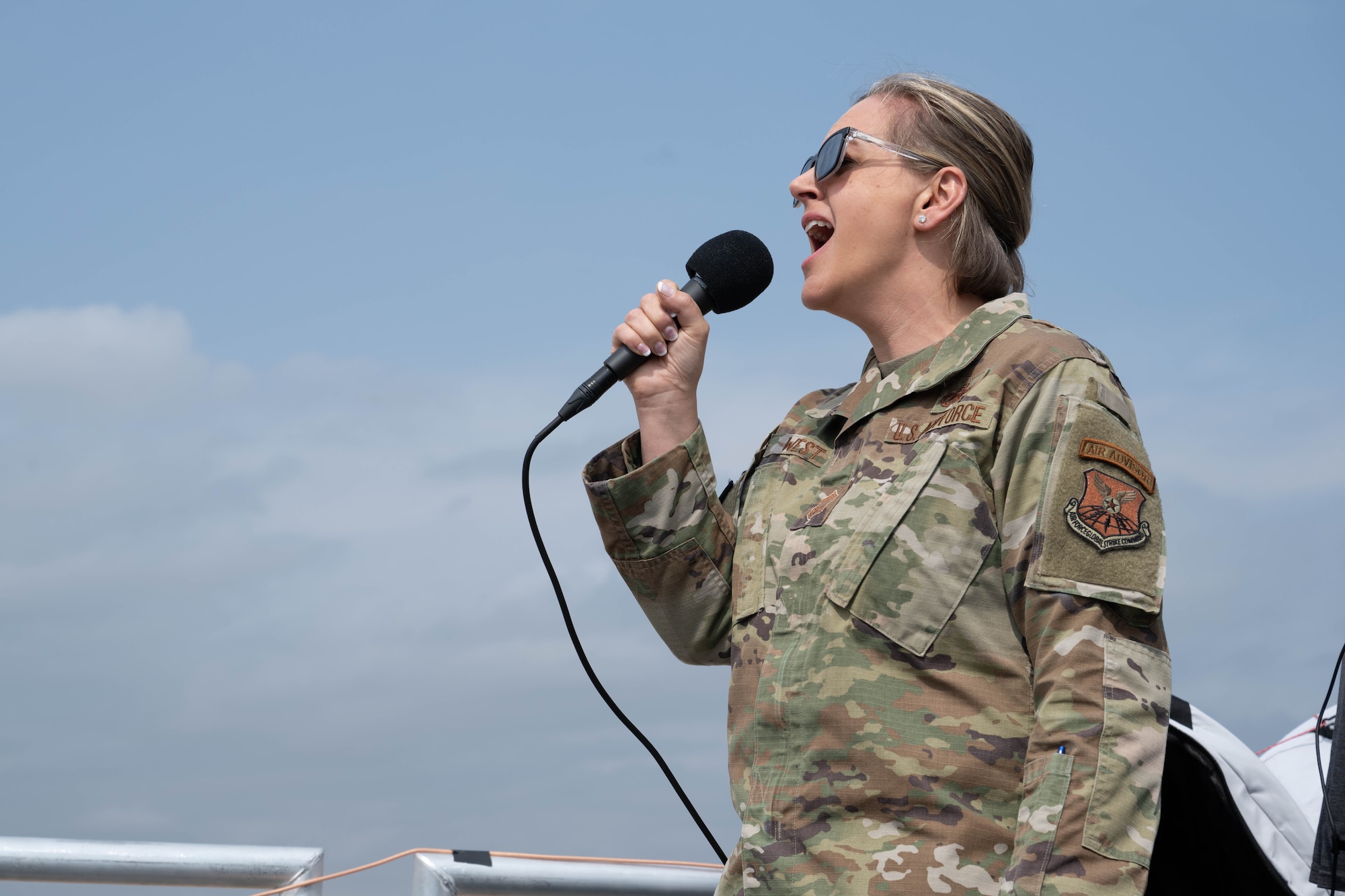 a female in uniform sings a song into a microphone