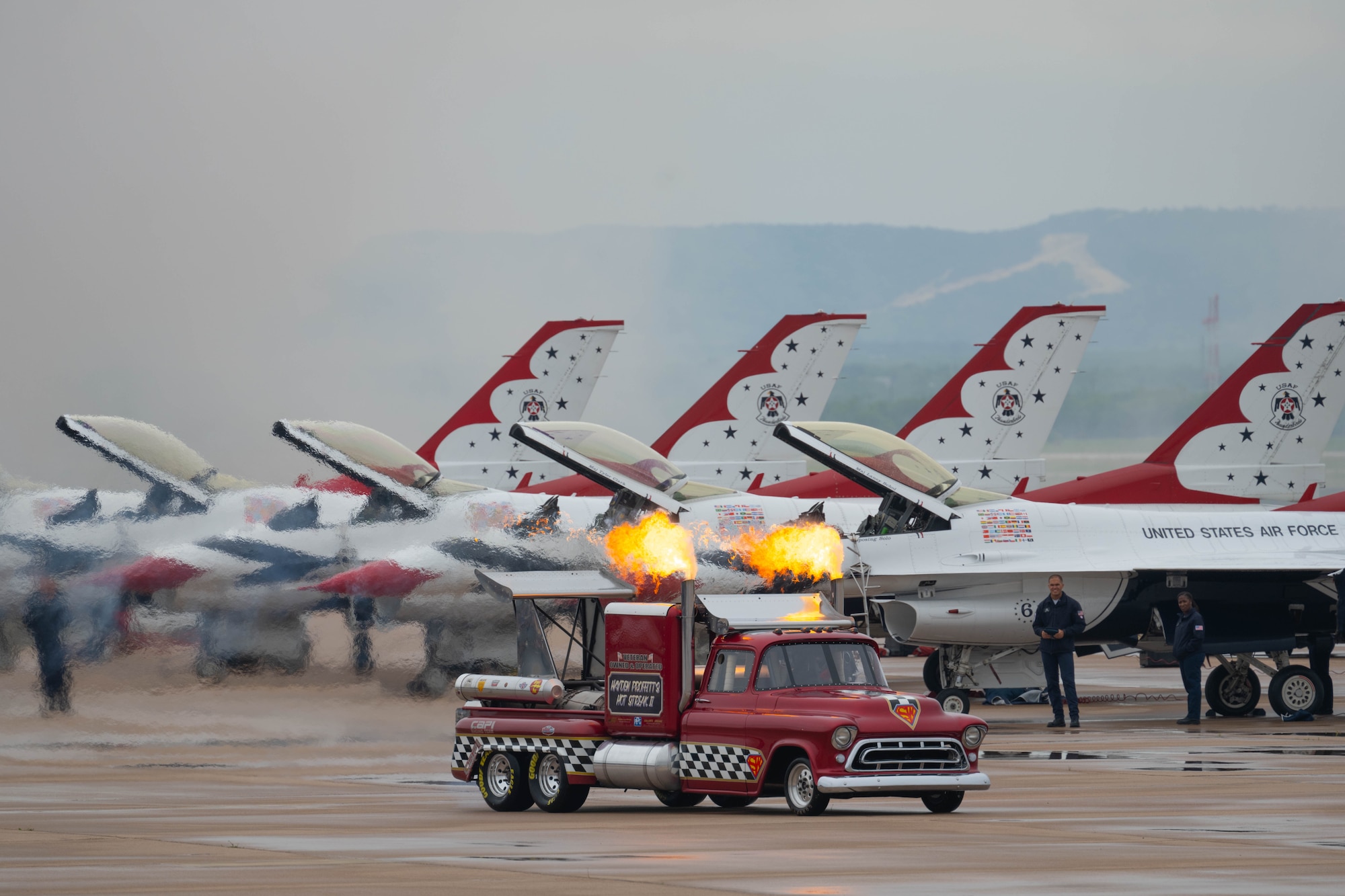a jet truck drives on the flightline in front of f-16's on the flightline