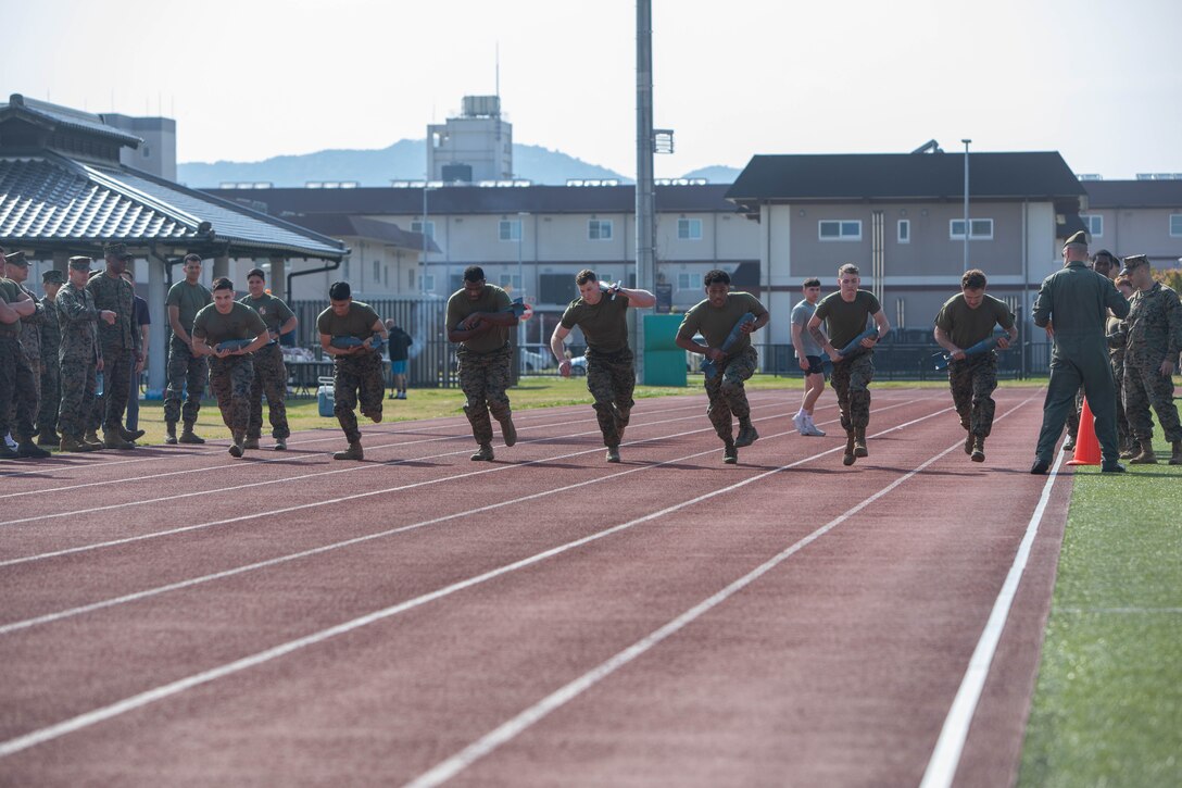 U.S. Marines from Marine Corps Air Station Iwakuni, conduct a relay race during the monthly “Ace of the Base” competition at MCAS Iwakuni, Japan, April 17, 2025. Ace of Base is a competition hosted by Marine Aircraft Group 12 and open to all units aboard MCAS Iwakuni to promote competitiveness, comradery, and physical fitness. This iteration consisted of a 4x400 meter relay race while carrying a 25-pound simulated bomb. (U.S. Marine Corps photo by Cpl. Dahkareo Pritchett)