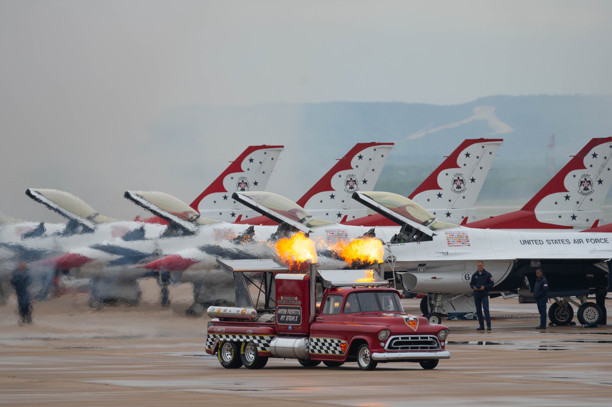 a jet truck drives on the flightline in front of f-16's on the flightline