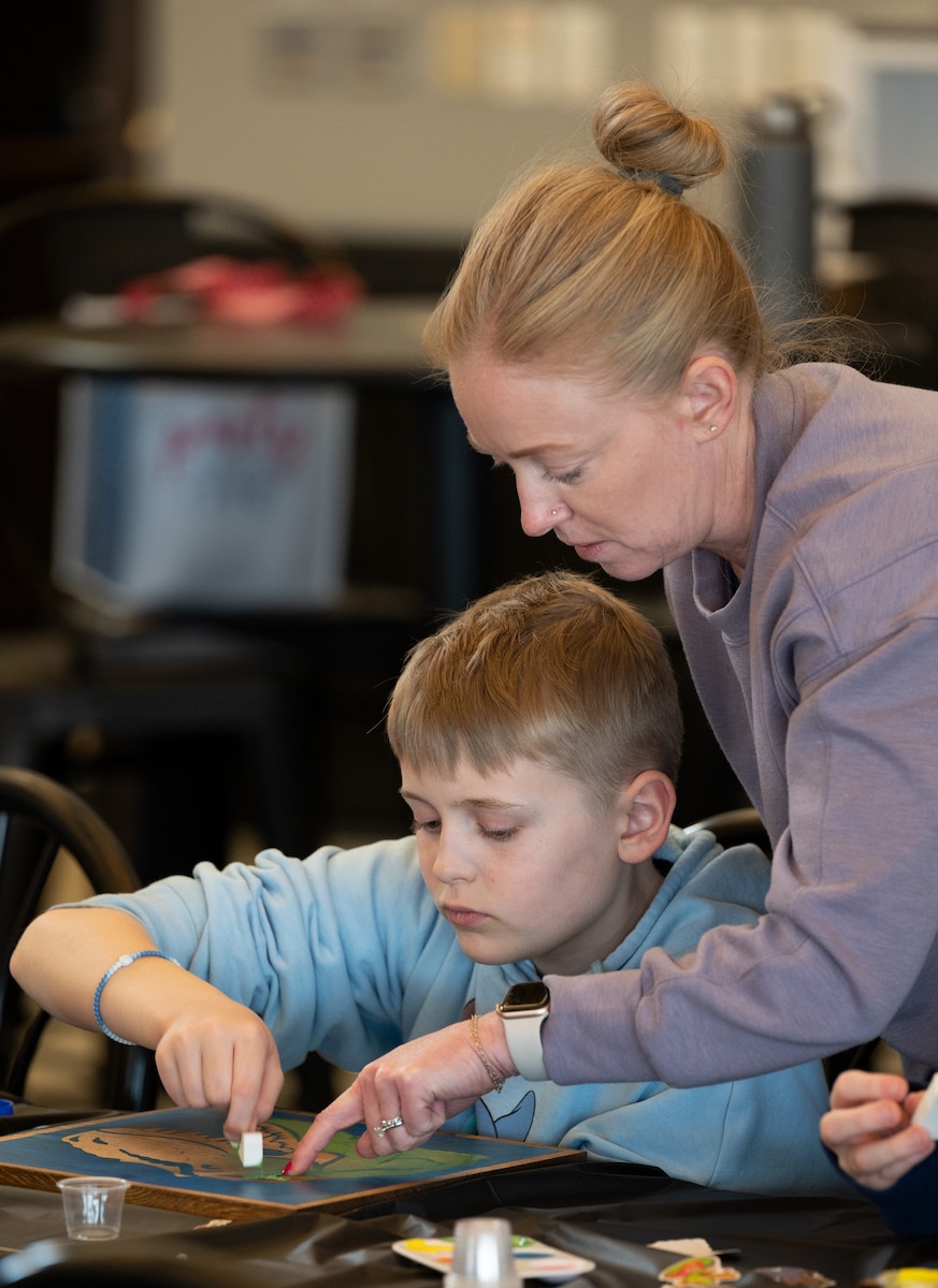 Woman guides child during art contest.