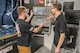 Two men are seen working on a machine.