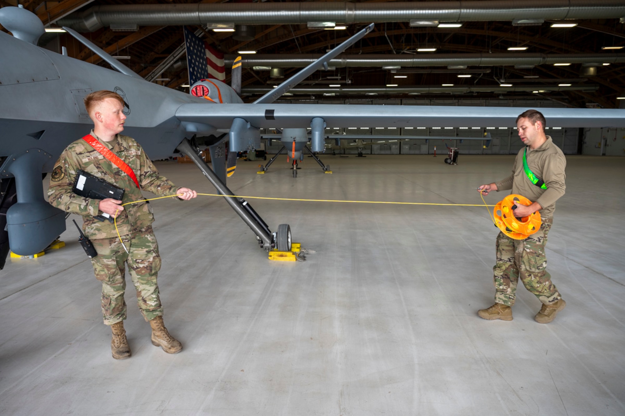 U.S. Air Force Senior Airman Sawyer Noland, 29th Aircraft Maintenance Unit assistant dedicated crew chief, left, and U.S. Air Force Tech. Sgt. Christian Osby, 29th AMXS dedicated crew chief, conduct a post-flight inspection on an MQ-9 Reaper at Holloman Air Force Base, New Mexico, April 2, 2025. Project Iron Agility is a dynamic training exercise designed to sharpen Airmen's deployment readiness skills through agile operations featuring F-16 Fighting Falcons, MQ-9s, and integrated logistics support. (U.S. Air Force photo by Senior Airman Michelle Ferrari)