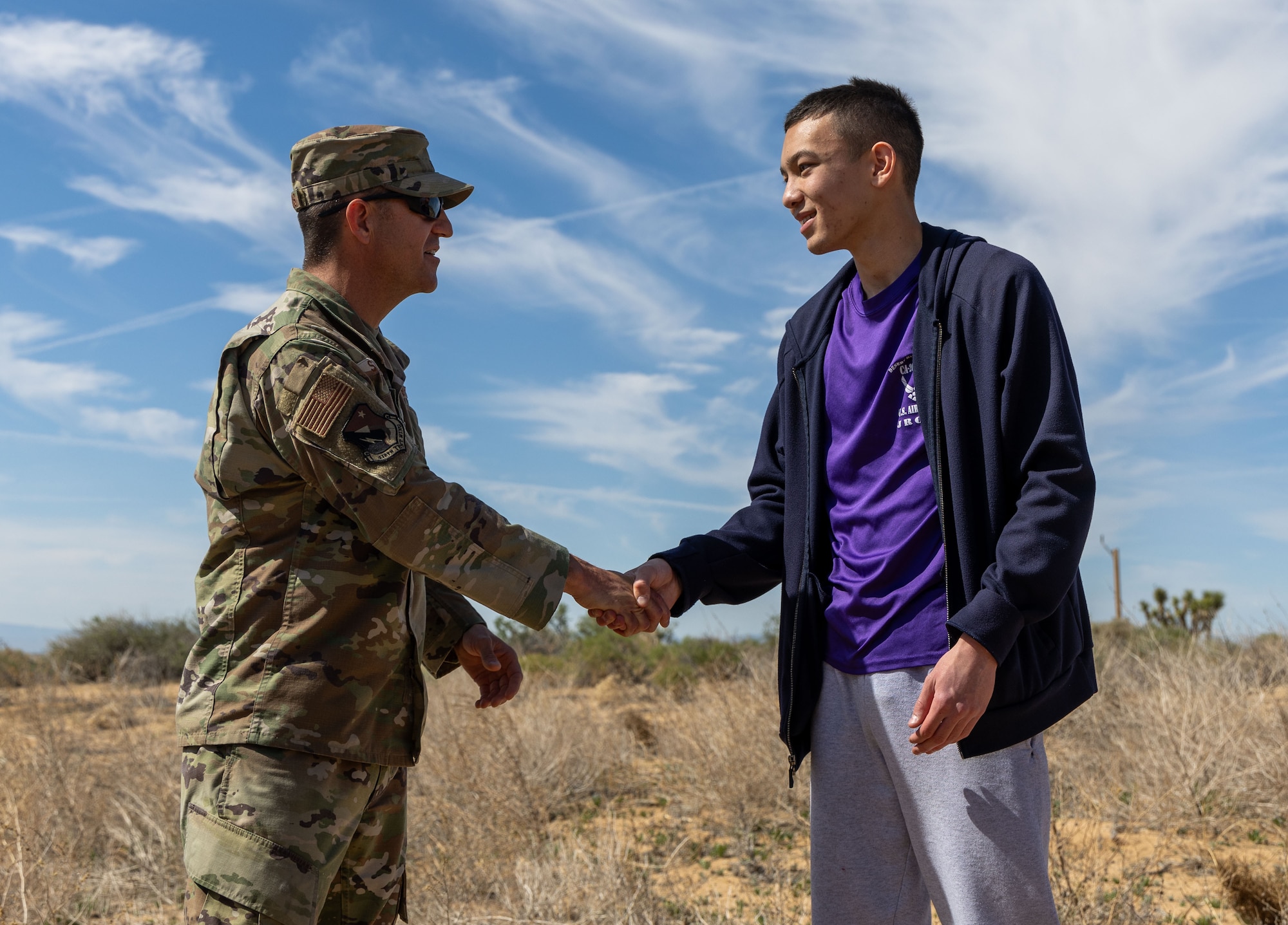 Chief Master Sgt. Justin Stoltzfus, 412th Test Wing command chief, gives a challenge coin to Aidan Vansickle, Desert Junior-Senior High School Air Force Junior ROTC cadet captain, for kicking off the commemorative Bataan Death March with a speech at Edwards Air Force Base, California, April 12. (Air Force photo by Jennifer Healy)