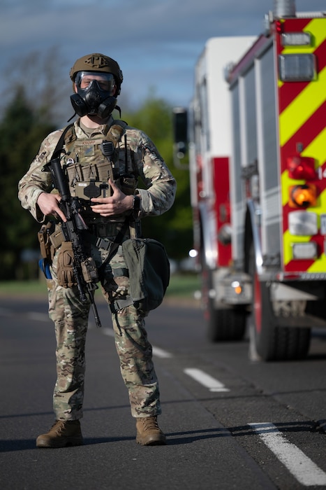 Person standing guard alongside a fire truck with a weapon.