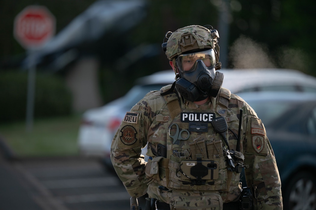 A person with a gas mask walks across a parking lot.