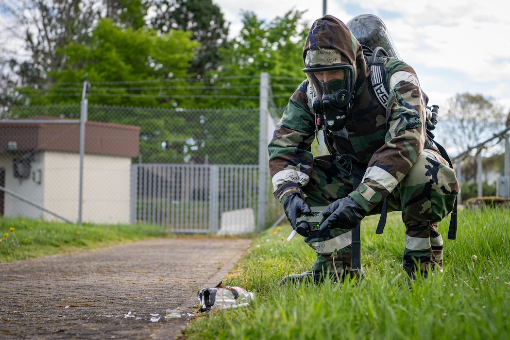 A person uses a device to test the air around a broken glass bottle.