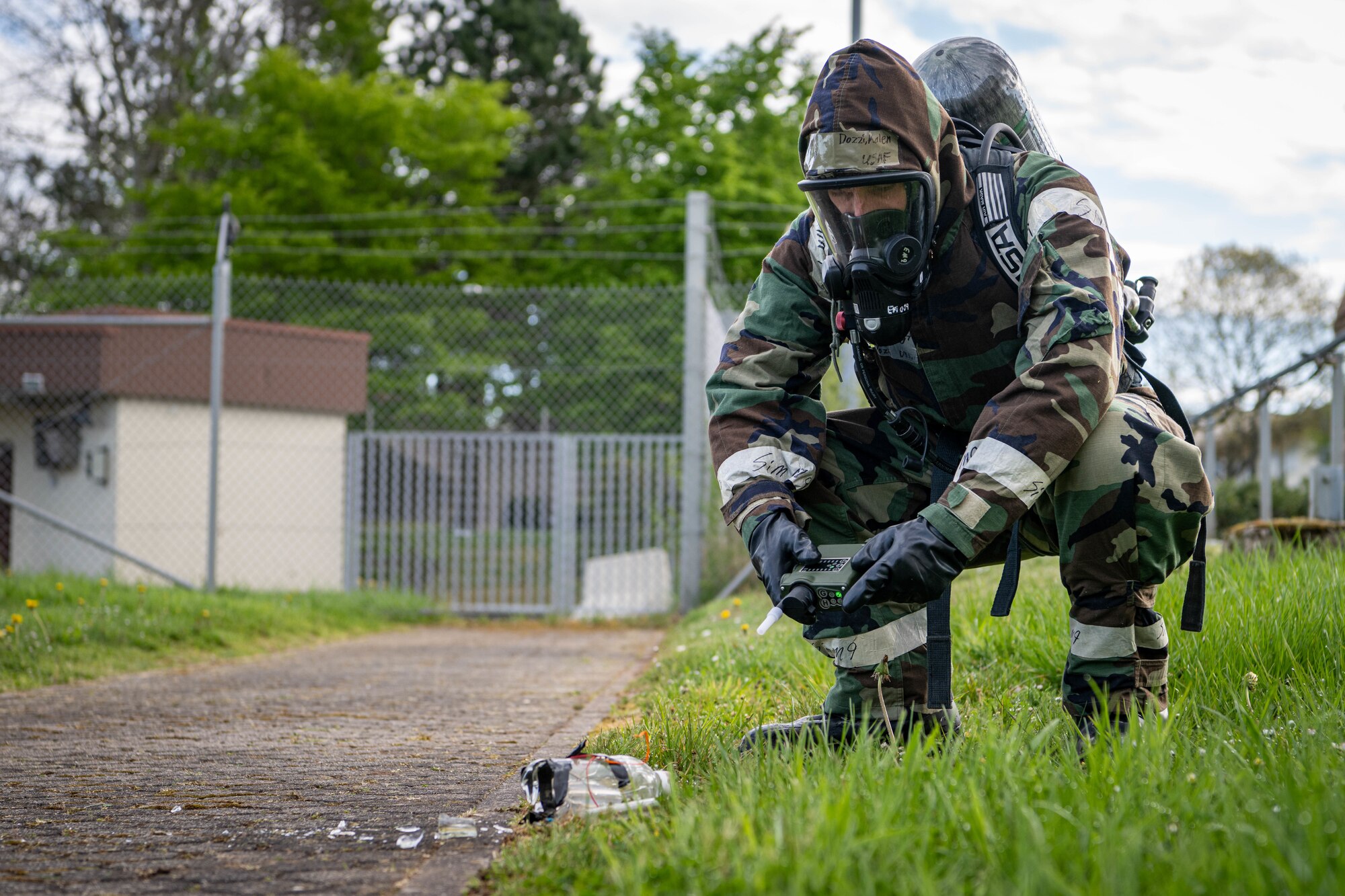 A person uses a device to test the air around a broken glass bottle.