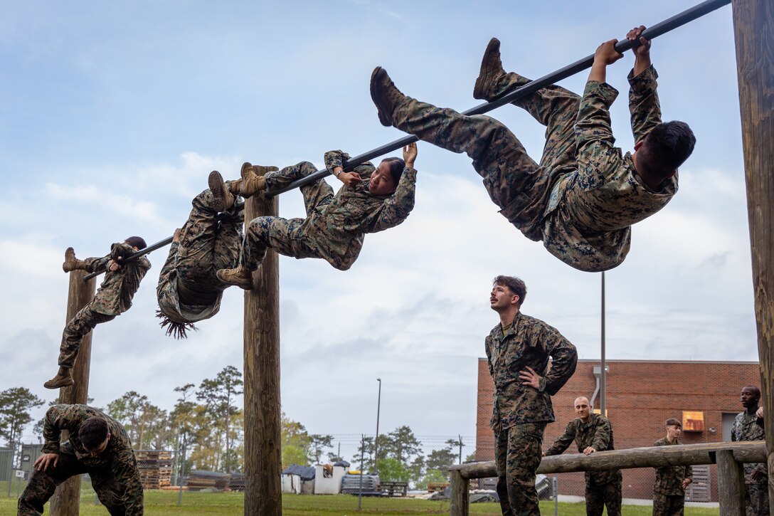 U.S. Marines with the 26th Marine Expeditionary Unit hurdle over the up-and-over bar while completing a Marine Corps obstacle course as part of a Marine Corps Martial Arts Program event at Camp Lejeune, North Carolina, April 4, 2025. MCMAP is a rigorous training program that teaches Marines hand-to-hand and close quarters combat skills and regularly makes use of the Marine Corps obstacle course to test Marines' strength, agility, and ability to persevere through fatigue. (U.S. Marine Corps Photo by Lance Cpl. Jack Labrador)