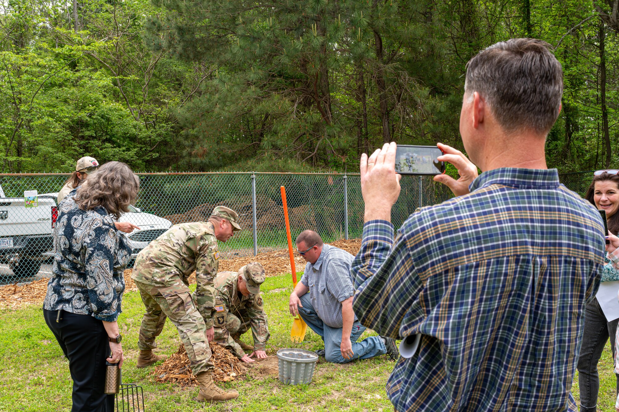 Donald Calder takes a photo of Joint Base Langley-Eustis leadership planting a Red Mulberry tree sapling