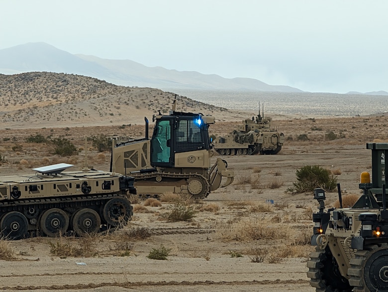 ERDC's Robotics for Engineer Operations (REO) unmanned bulldozer, developed by a team of research engineers from CERL, GSL, GRL and ITL, stands by after completing the lane proofing mission as Security Forces move through the breach lane.