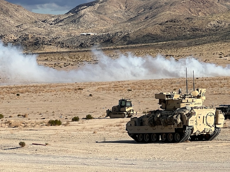 As U.S. forces begin a simulated mission, ERDC's Robotics for Engineer Operations (REO) unmanned bulldozer, designed by research engineers from ERDC’s CERL, GSL, GRL and ITL, lines up with the breach lane to support maneuver operations.