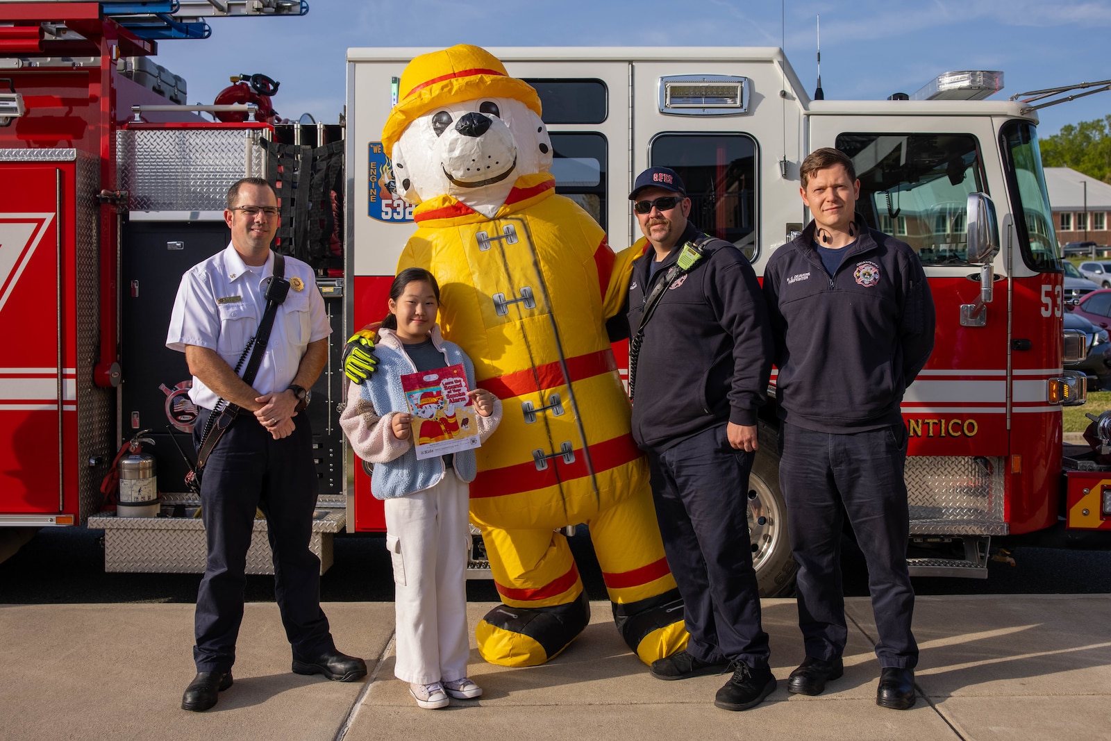 Quantico Fire and Emergency Services personnel pose for a photo with Hyunah Oh during a fire truck ride on Marine Corps Base Quantico, Virginia, Apr. 18, 2025. Quantico Fire and Emergency Services hosted a fire truck ride for winners of the 2024 Fire Prevention Week Coloring contest. The fire truck picked up the students from their base address and drove them to Crossroads Elementary School. (U.S. Marine Corps photo by Lance Cpl. Federico Marquez)