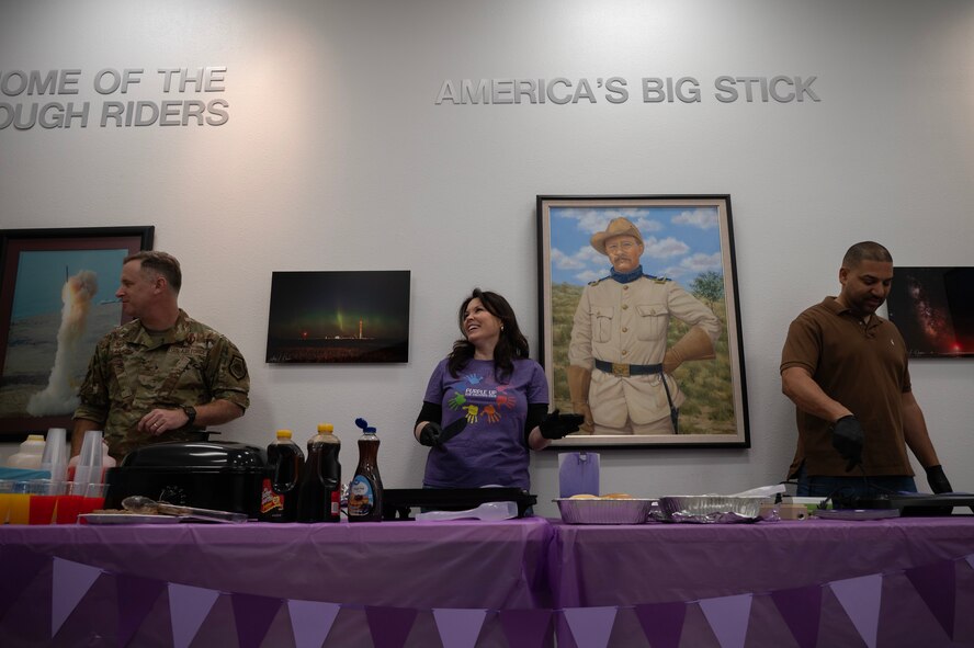 U.S. Air Force Col. James Schlabach, 91st Missile Wing (MW) commander (left), his wife Monica Schlabach (center) and Detrick Thomas, spouse of Chief Master Sgt. Becky Thomas, 91 MW Command Chief Master Sergeant (right), prepare breakfast for military children at Minot Air Force Base, North Dakota, April 18, 2025. The breakfast allowed children and families to celebrate the Month of the Military Child together. (U.S. Air Force photo by Senior Airman Alyssa Bankston)