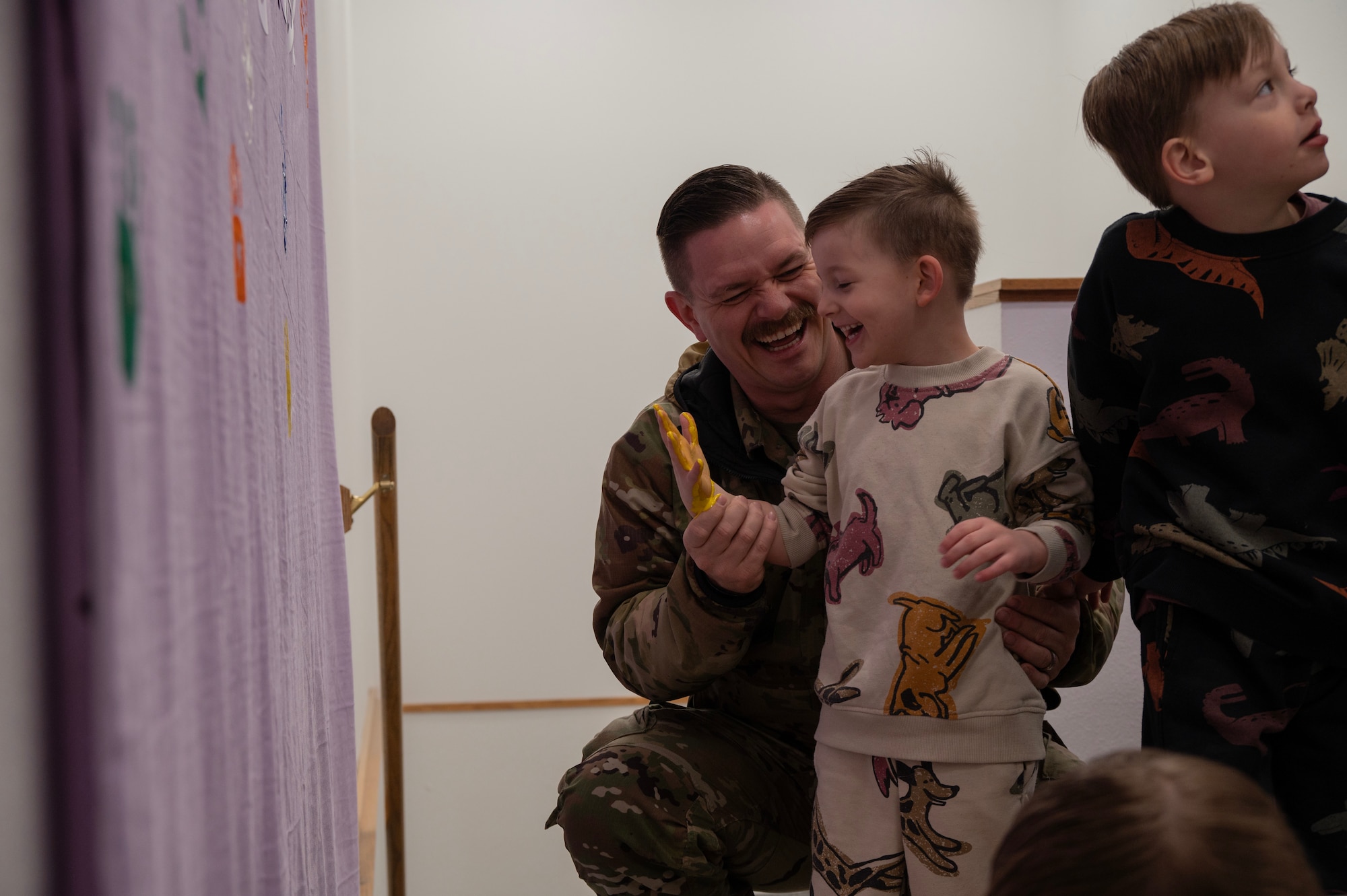 Team Minot families paint a banner during the 91st Missile Wing (MW) Family Day at Minot Air Force Base, North Dakota, April 18, 2025. The 91MW hosted the family day in honor of the Month of the Military Child. (U.S. Air Force photo by Senior Airman Alyssa Bankston)
