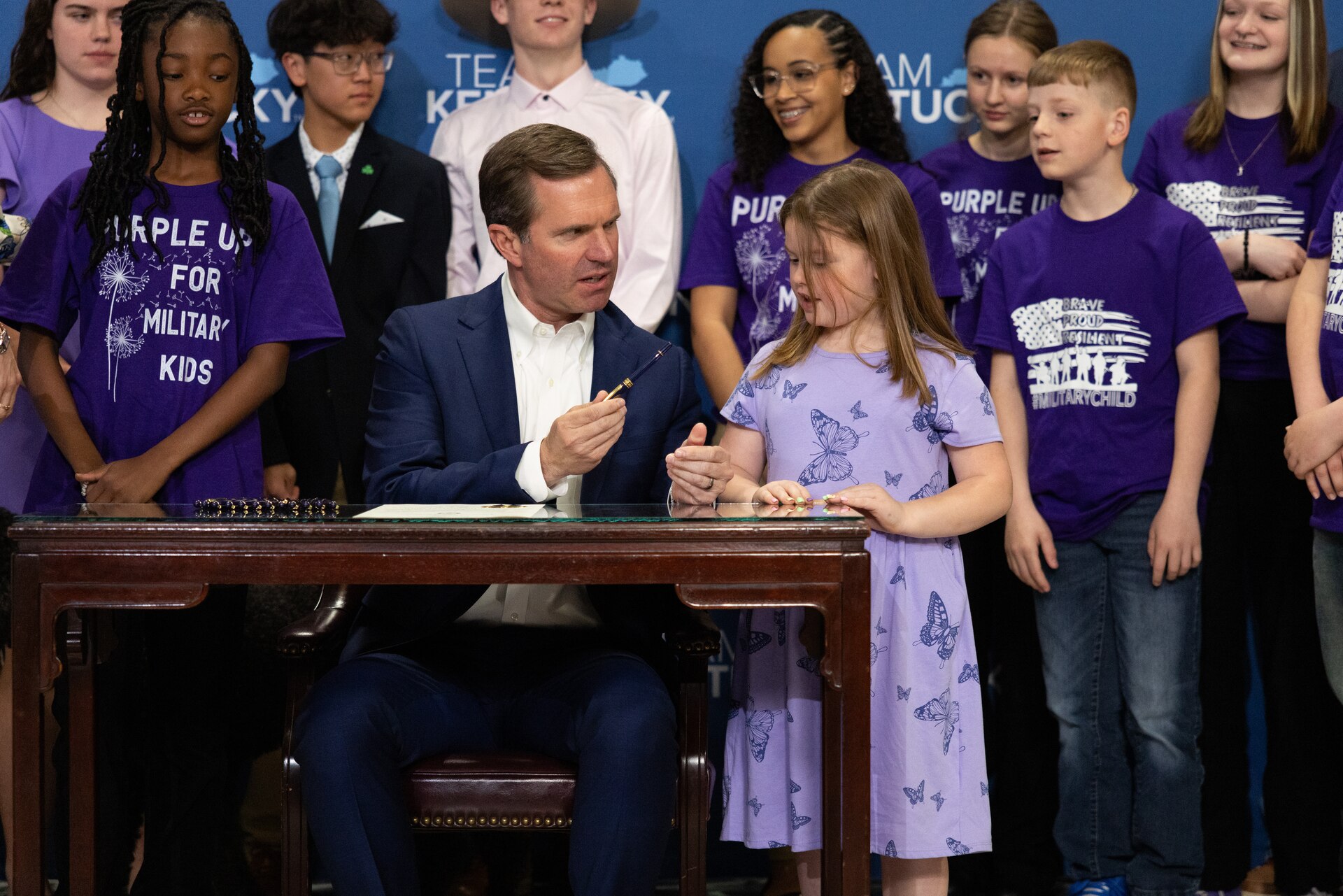 Kentucky Gov. Andy Beshear shows the pen he uses to sign proclamations to the daughter of a Service member at the Kentucky State Capitol Rotunda in Frankfort, Ky., on April 17, 2025.  Beshear signed the official proclamation that April is the month of the military child to show appreciation for Service members’ families. (U.S. Army National Guard photo by Andy Dickson)