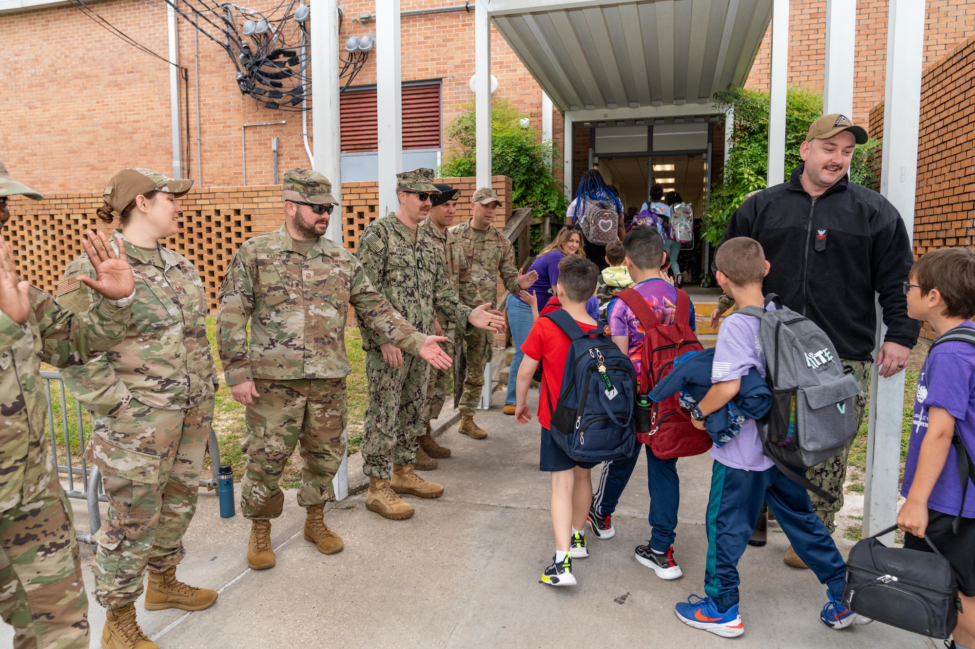 U.S. Airmen assigned to Keesler Air Force Base and Sailors assigned to the Naval Construction Battalion Center Gulfport greet children as they arrive at school during Purple Up Day at Back Bay Elementary, Biloxi, Mississippi, April 15, 2025. Purple Up Day is a way to show appreciation for the sacrifices made by military families and to recognize the unique challenges and resilience of military children. (U.S. Air Force photo by Andrew Young)