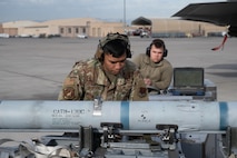 U.S. Air Force Staff Sgt. Mark Anthony Mangune, a 57th Aircraft Maintenance Squadron (AMXS) crew chief, checks a missile before loading it as Senior Airman Brighton Robinson, a 57th AMXS load crew member, operates a jammer during the first quarter weapons standardization load crew competition at Nellis Air Force Base, Nevada, April 18, 2025