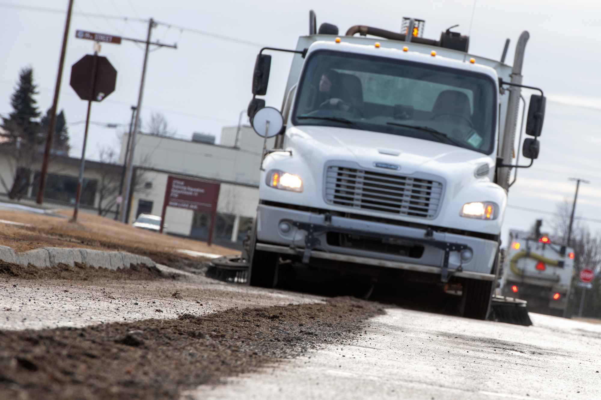 A street sweeper collects debris on Luke Avenue at Joint Base Elmendorf-Richardson, Alaska, March 12, 2025. The 773d Civil Engineer Squadron is transitioning from seasonal snow removal duties to clearing winter detritus from roadways and maintenance for the safety of base traffic.