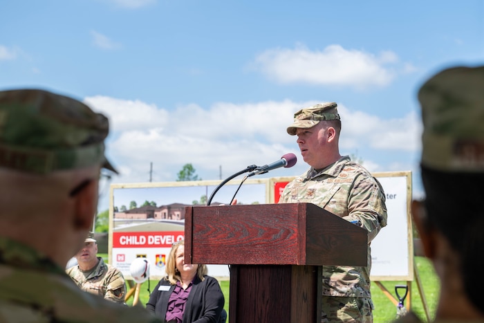 A man in a military uniform stands at a podium and speaks.