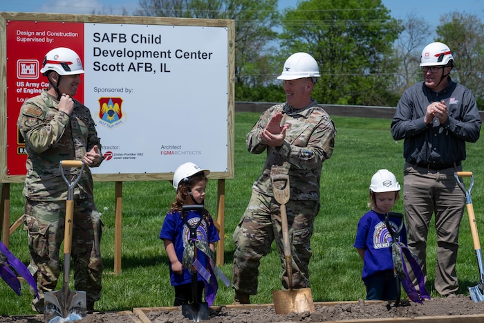 2 Airmen and one Civilian Contractor clap and smile at each other.