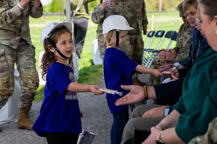 Child with a hard hat on passes out cookies to the crowd