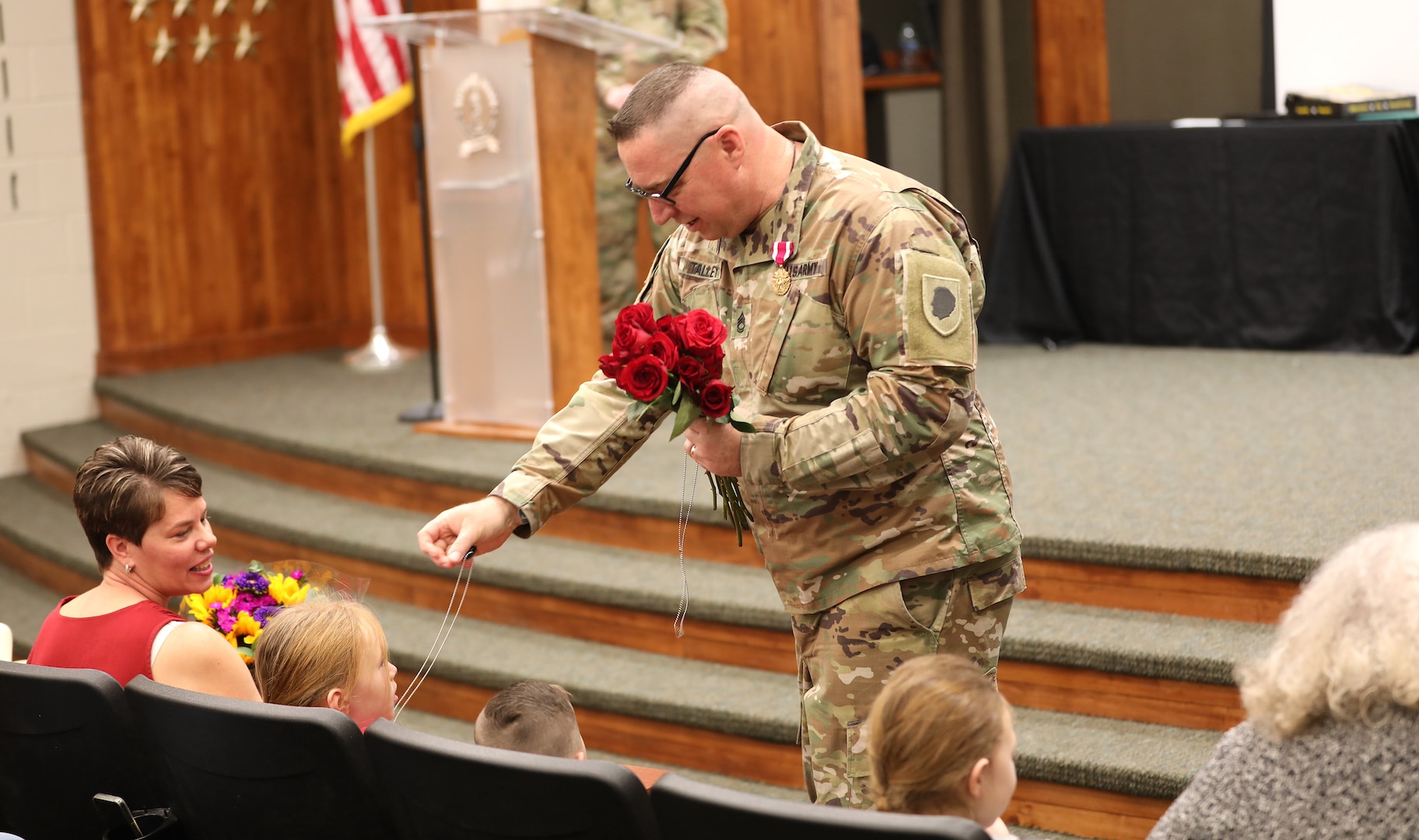 Sgt. 1st Class Britt Talley presents a bouquet of roses and dog tags to family members during his retirement ceremony April 18 at Camp Lincoln in Springfield, Illinois. The gesture honored the love and support his family provided throughout his 31-year military career.
(U.S. Army photo by 2nd Lt. Trenton Fouche, Joint Force Headquarters – Illinois National Guard)