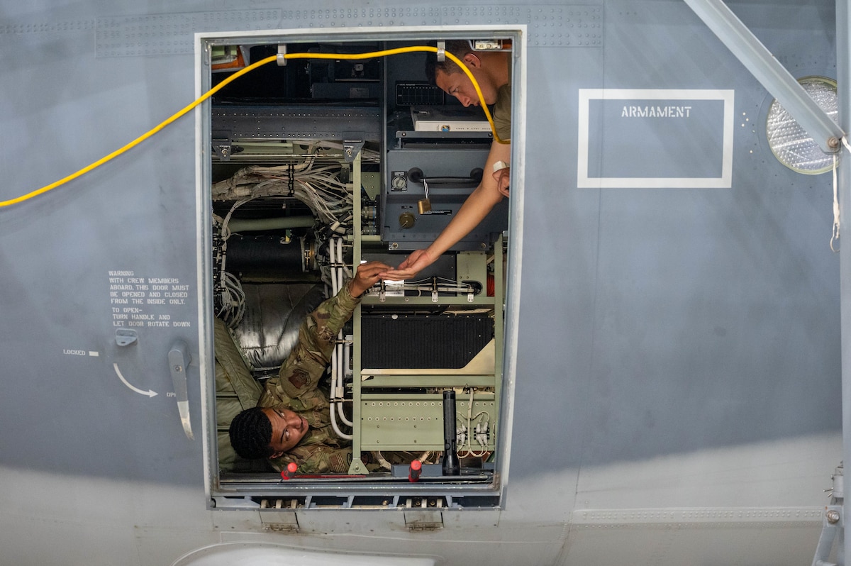 Senior Airman Brandon Hamdan hands Senior Airman Alexander Rodriguez screws.