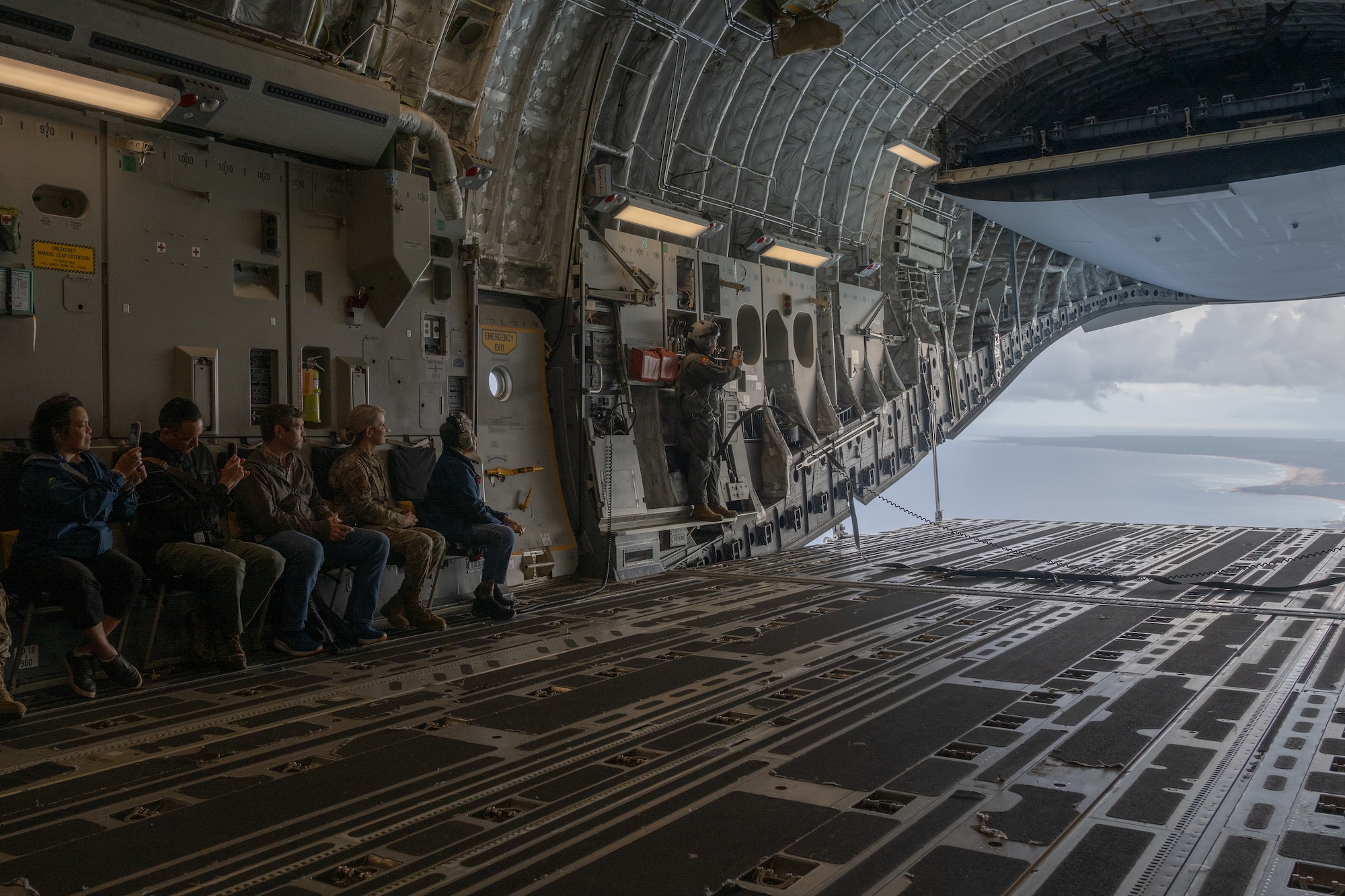 State of Hawaiʻi representatives and DoD personnel look out the back of a C-17 Globemaster III, from Joint Base Pearl Harbor-Hickam, during a mission off the coast of the state of Hawaiʻi, April 17, 2025. The flight showcased the importance of the Air Force and Space Force mission in Hawaiʻi and its critical role to ensure stability and security in the Indo-Pacific. (U.S. Air Force photo by Tech. Sgt. Emerson Nuñez)