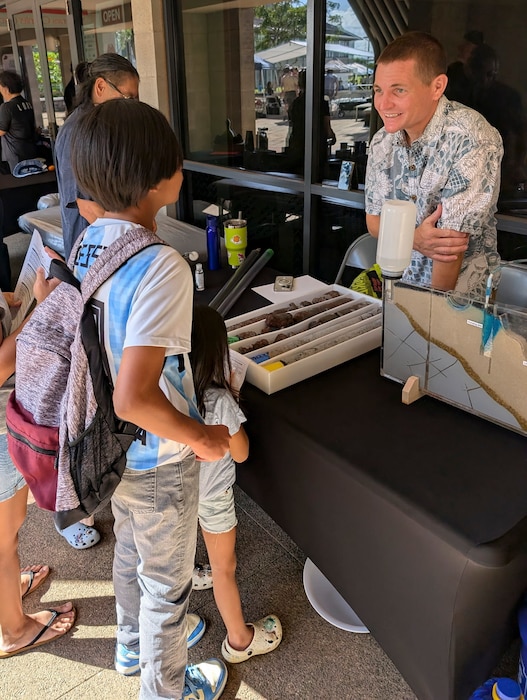 KAPOLEI, Hawaii (April 5, 2025) Cmdr. Benjamin Dunn, deputy for environment and remediation, Navy Closure Task Force-Red Hill (NCTF-RH), speaks with guests at the ninth annual Onizuka Day of Exploration held at the University of Hawaii-West Oahu in Kapolei, Hawaii, April 5, 2025. The local science, technology, engineering and mathematics (STEM) event provided an opportunity for the local community to engage with scientists and engineers from NCTF-RH and Commander, Navy Region Hawaii and learn about NCTF-RH STEM-related operations as part of their mission to safely close the Red Hill Bulk Fuel Storage Facility.  (U.S. Navy photo by Lt. Naadia Puri)