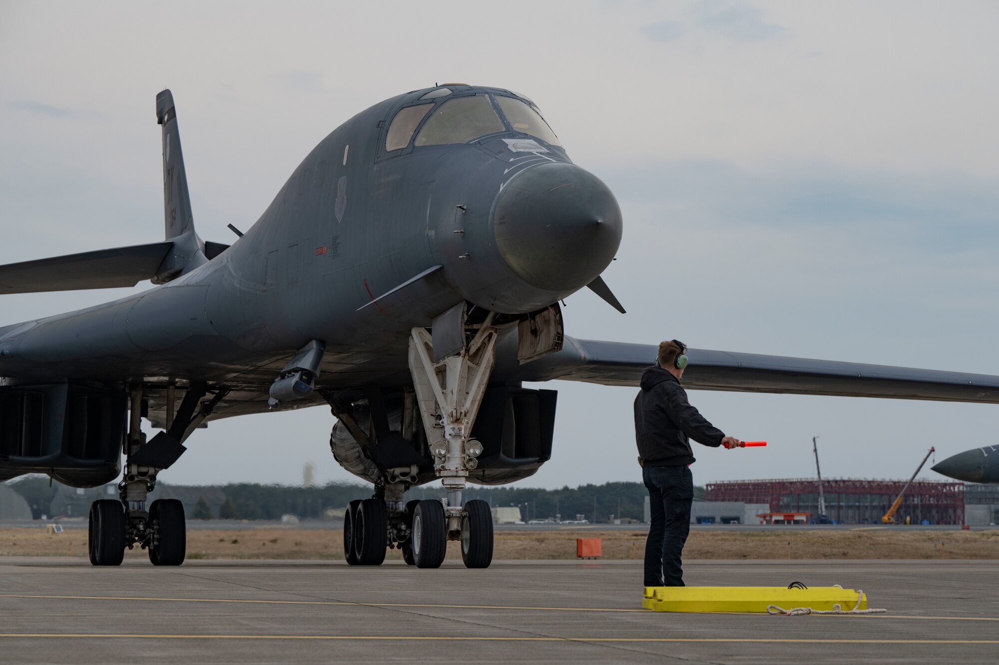 U.S. Air Force Senior Airman Christopher Collins, 9th Expeditionary Bomb Squadron crew chief, marshals a B-1B Lancer at Misawa Air Base, Japan, in support of Bomber Task Force 25-2, April 18, 2025. Bomber Task Force deployments contribute to integrated deterrence by showcasing conventional and nuclear capabilities, signaling U.S. strength and resolve. (U.S. Air Force photo by Senior Airman Emma Anderson)