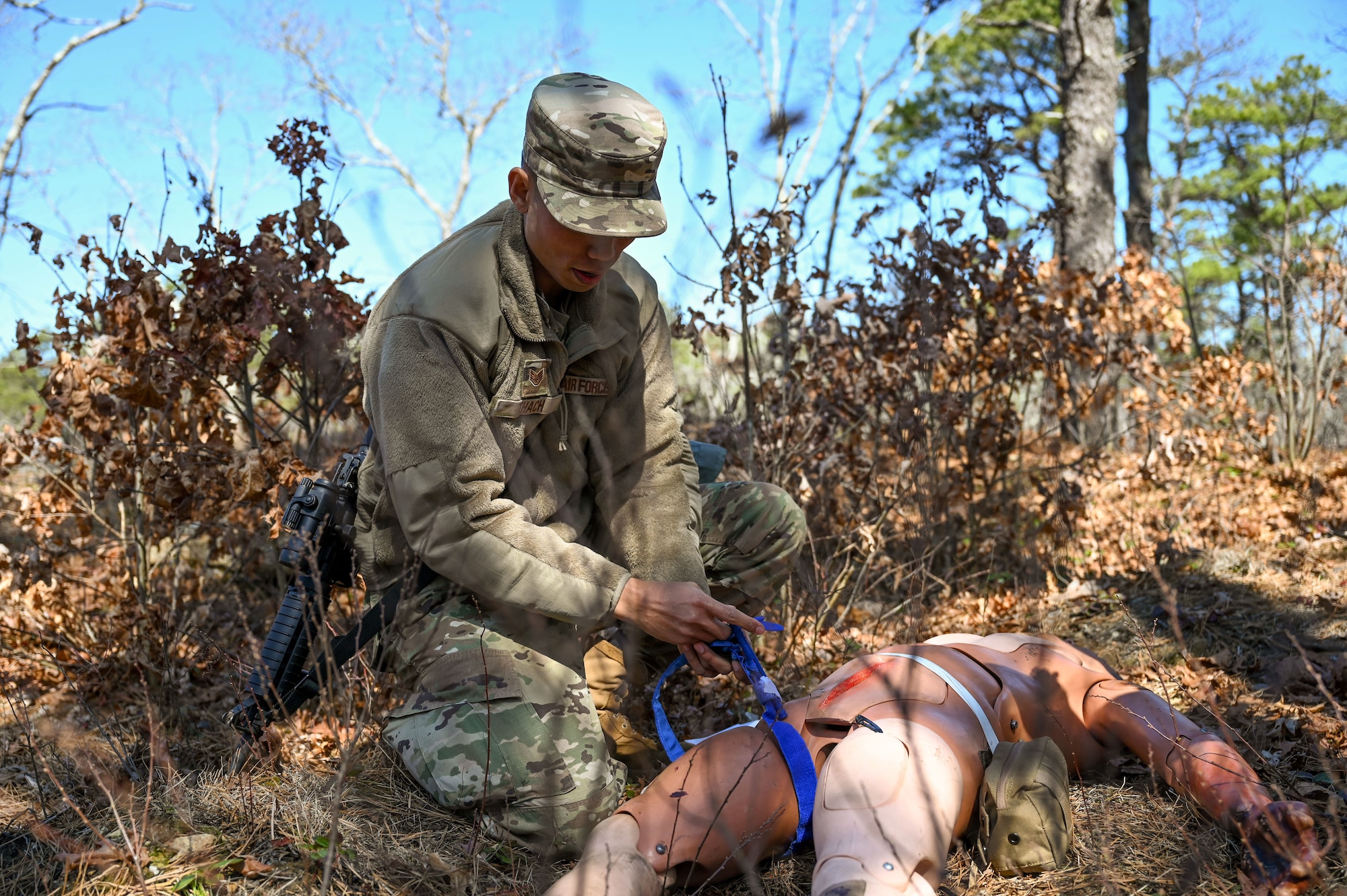 Airman applies a tourniquet to a manikin.