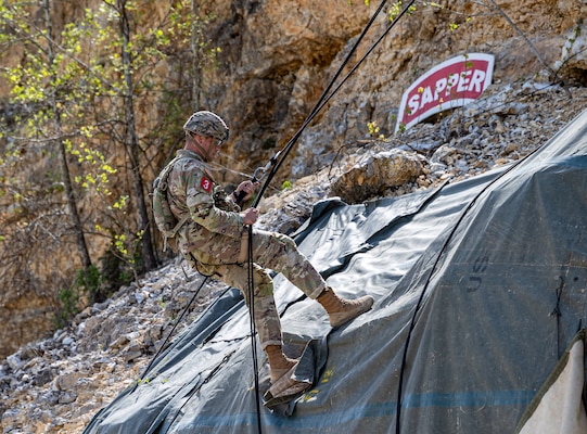 a Soldier is seen repelling down a cliff.