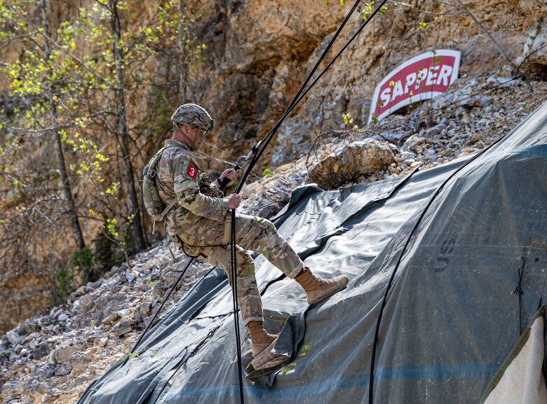 a Soldier is seen repelling down a cliff.