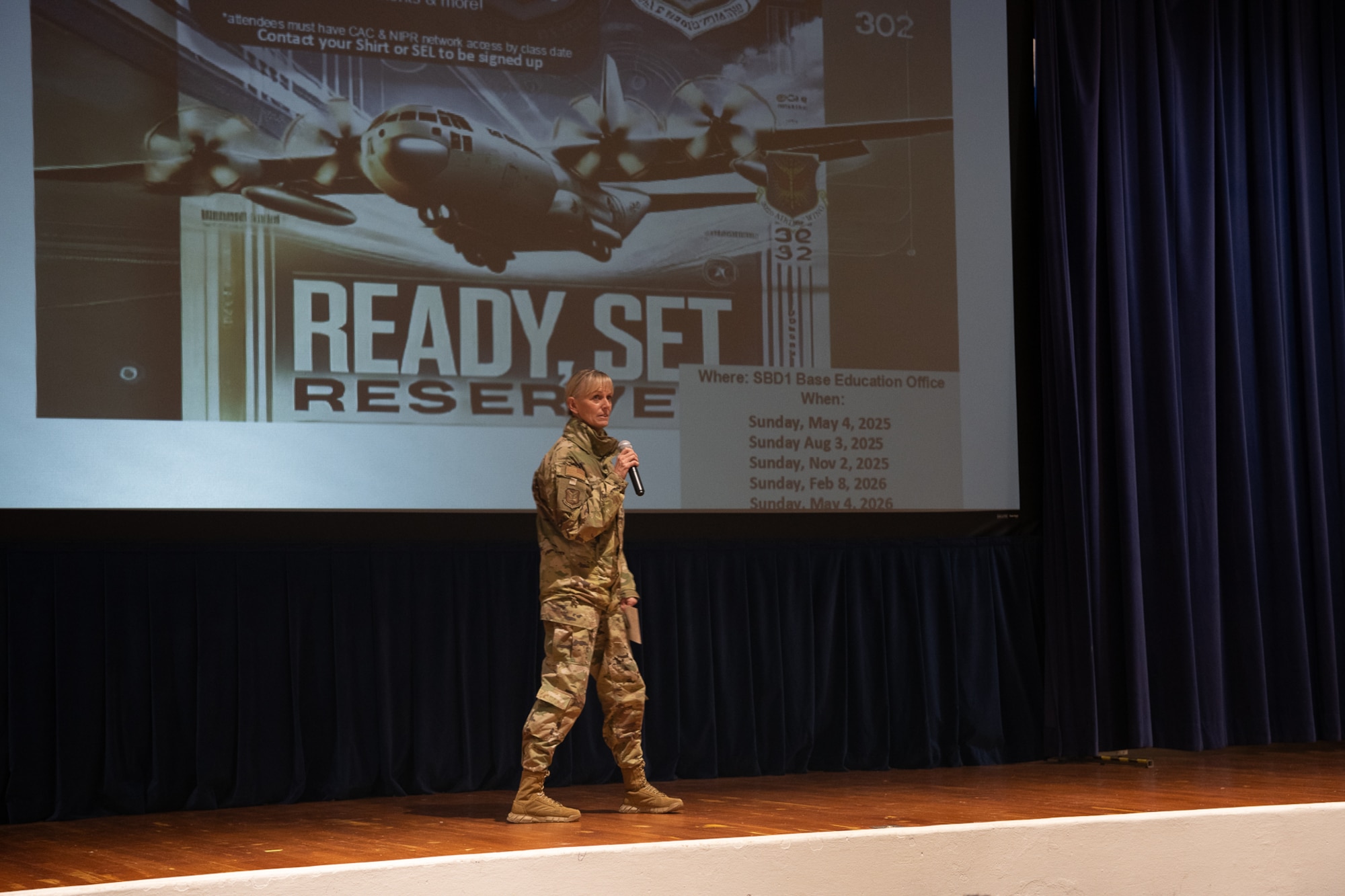 A woman in military uniform holding a microphone on stage.