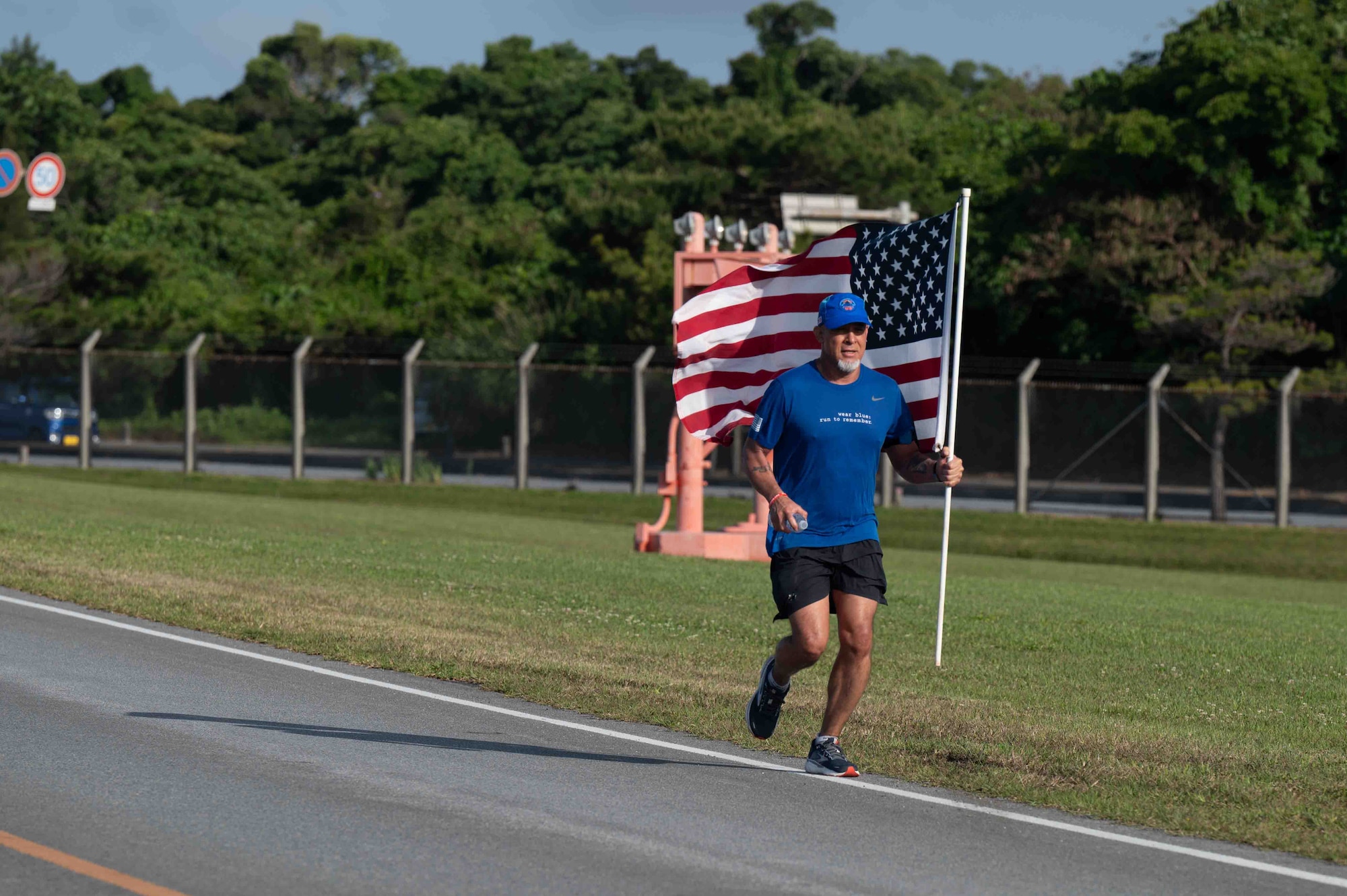 Service member runs with a flag in the Bataan March.