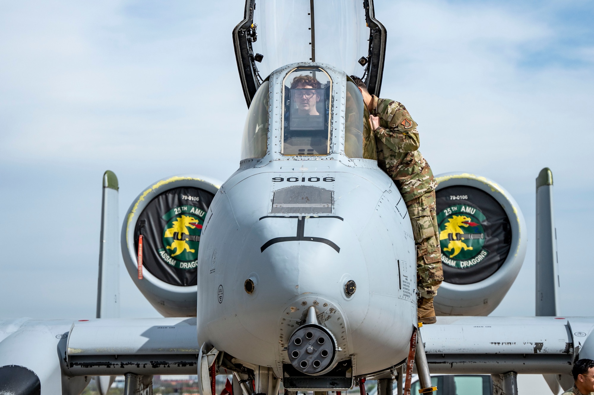 A person sits in a jet while getting instructions on what the cockpit equipment does.