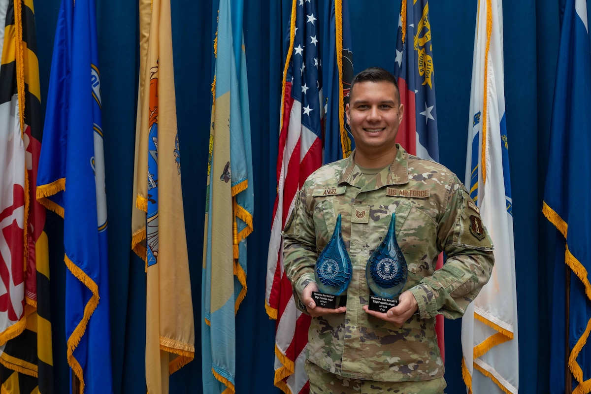 Tech. Sgt. Franklin Angel, poses for a photo in front of flags with two awards.