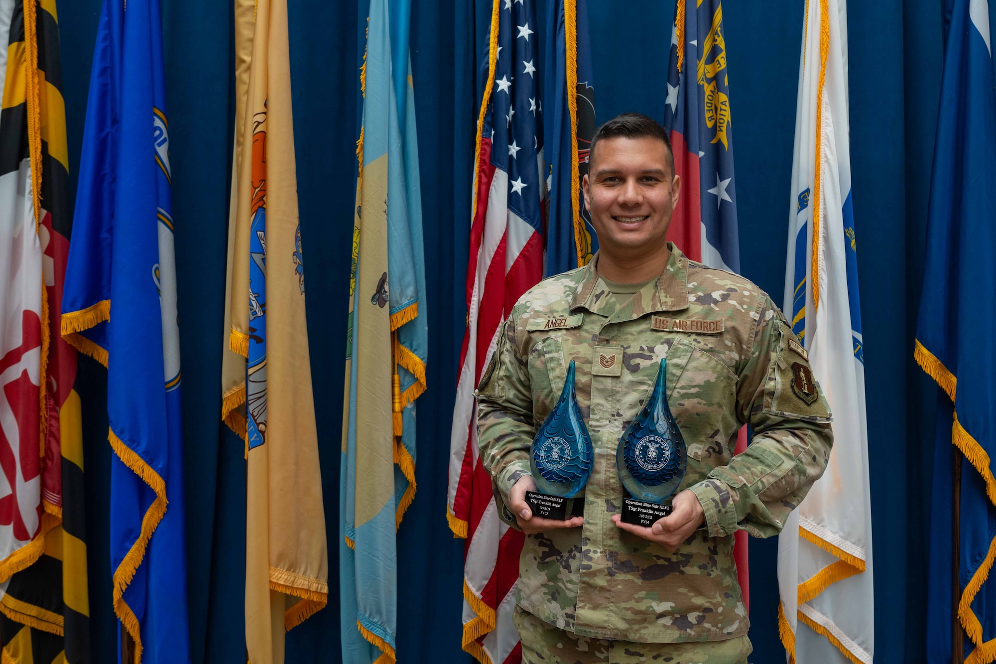Tech. Sgt. Franklin Angel, poses for a photo in front of flags with two awards.