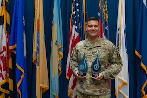 Tech. Sgt. Franklin Angel, poses for a photo in front of flags with two awards.