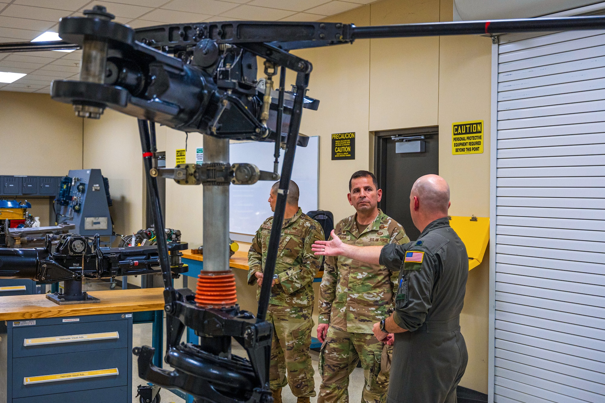 U.S. Air Force Col. Sergio Anaya, 62d Airlift Wing commander, center, listens to Lt. Col. Cary Reeves, 318th Training Squadron director of operations, explain helicopter maintenance course curriculum at the Inter-American Air Forces Academy at Joint Base San Antonio-Lackland, Texas, April 9, 2025.