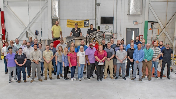 Fleet Readiness Center East (FRCE) and Defense Logistics Agency employees who have been part of the F402 team, either currently or in the past, stand in front of the depot’s final completed F402 engine. Following the conclusion of the command’s last AV-8 Harrier maintenance event in September, FRCE also returned its final F402 engine, the Harrier’s power source, to the fleet Oct. 28.