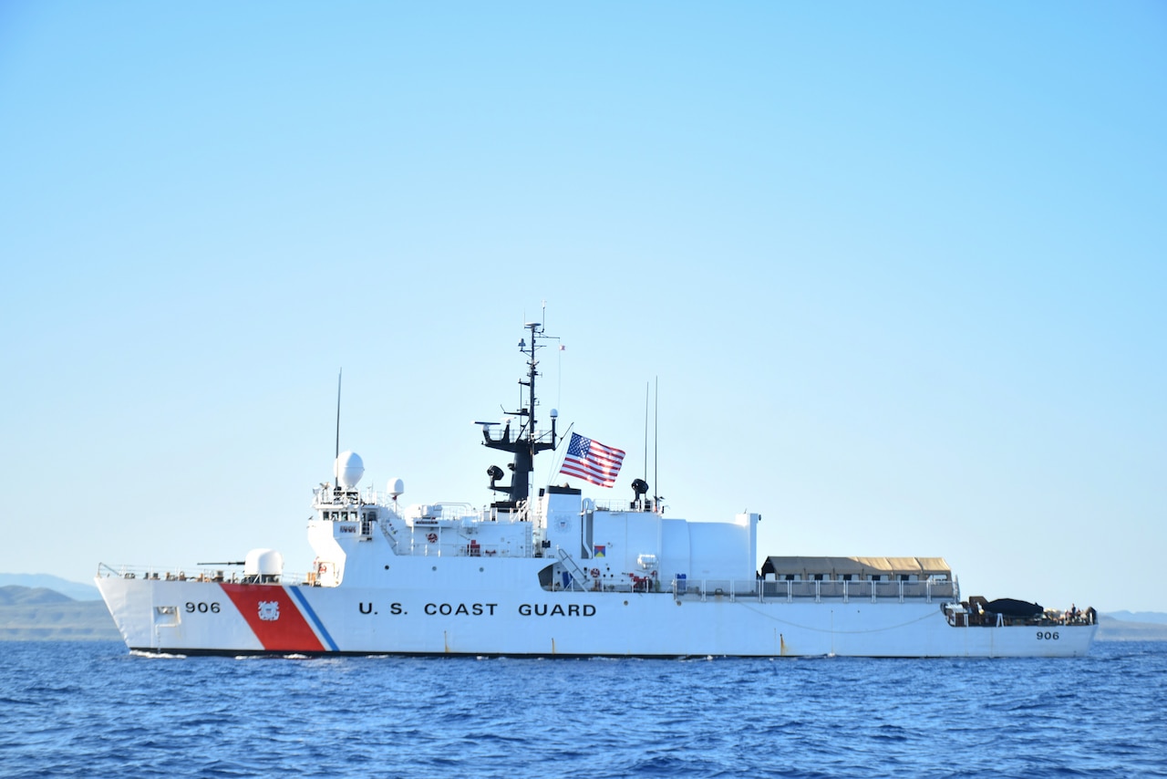 A large white vessel with the words U.S. Coast Guard on the side sails in the water.