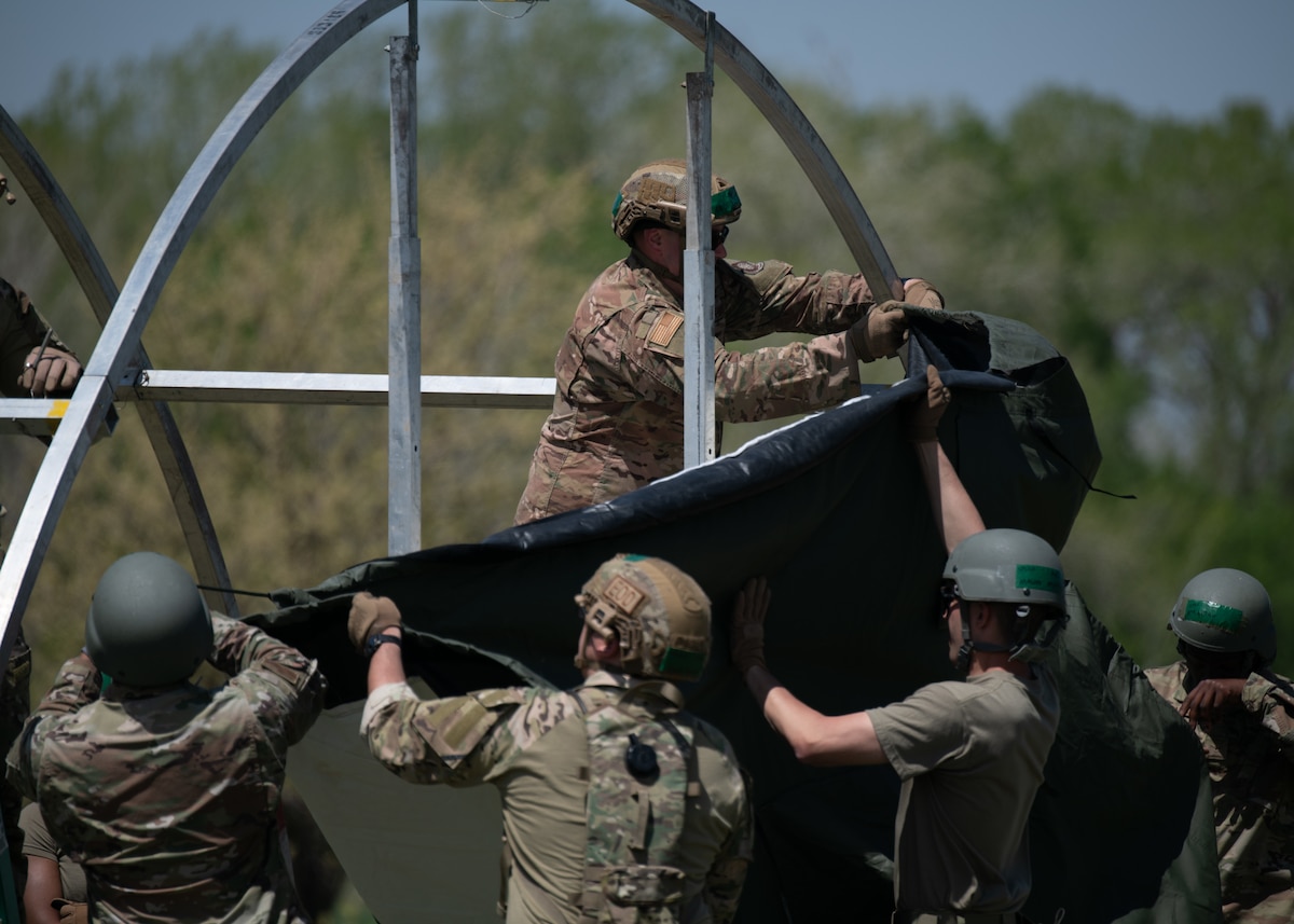 Airmen from the 22nd Civil Engineer Squadron work together to attach a tarp to their tent during the 22nd CES Battle of the Bulls competition at McConnell Air Force Base, Kansas, April 17, 2025. The event culminated with a tent-building competition in which each team had to construct a tent in the fastest time possible. (U.S. Air Force photo by Senior Airman Amelio Brown)