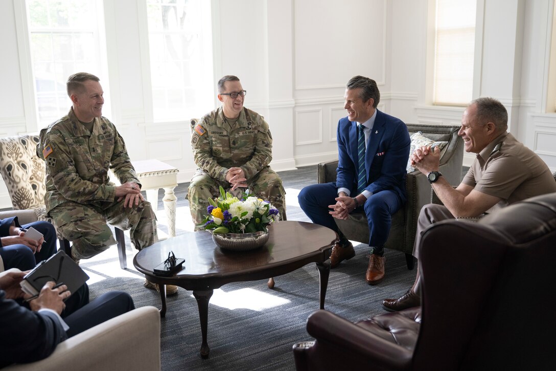 The defense secretary sits around a table with five other service members.