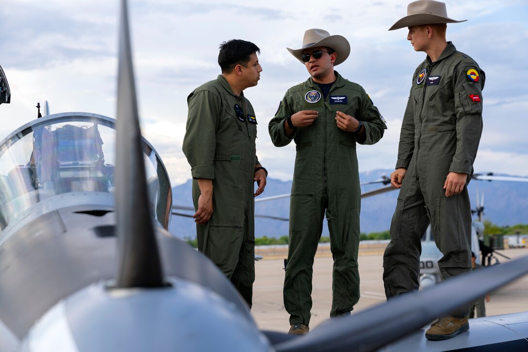 Colombian Air Force aircrew speak with a U.S. Marine on the wing of an A-29B Super Tucano aircraft during an exchange between Red Flag-Rescue 23-1 exercise participants at Davis-Monthan Air Force Base, Ariz., May 16, 2023. Exercises like Red Flag-Rescue present opportunities to build regional capacity with partner nations by enhancing cooperation, collaboration, and interoperability in a joint environment. (U.S. Air Force Photo by Tech. Sgt. Rachel Maxwell)