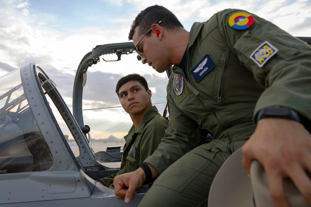 A Colombian Air Force aircrew member shows a U.S. Marine the cockpit of an A-29B Super Tucano aircraft during an exchange between Red Flag-Rescue 23-1 exercise participants at Davis-Monthan Air Force Base, Ariz., May 16, 2023. The multilateral combat search and rescue exercise is designed to enhance interoperability with joint-services alongside allied and partner nations. (U.S. Air Force Photo by Tech. Sgt. Rachel Maxwell)