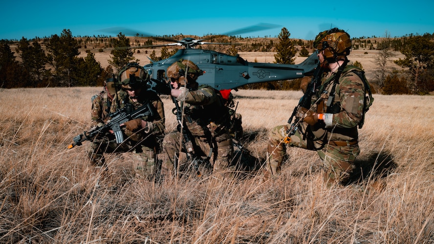 91st Missile Security Operations Squadron Tactical Response Force defenders prepare to advance uphill as a 550th Helicopter Squadron MH-139 Grey Wolf readies for takeoff during the Nuclear Convoy Course at Camp Guernsey Joint Training Center’s North Training Area, Wyoming, April 7, 2025. The 91 MSOS TRF air insertion marked the start of their participation in the NCC, a multi-day exercise sharpening convoy security, tactical response, and nuclear surety capabilities. (U.S. Air Force photo by Staff Sgt. Michael A. Richmond)