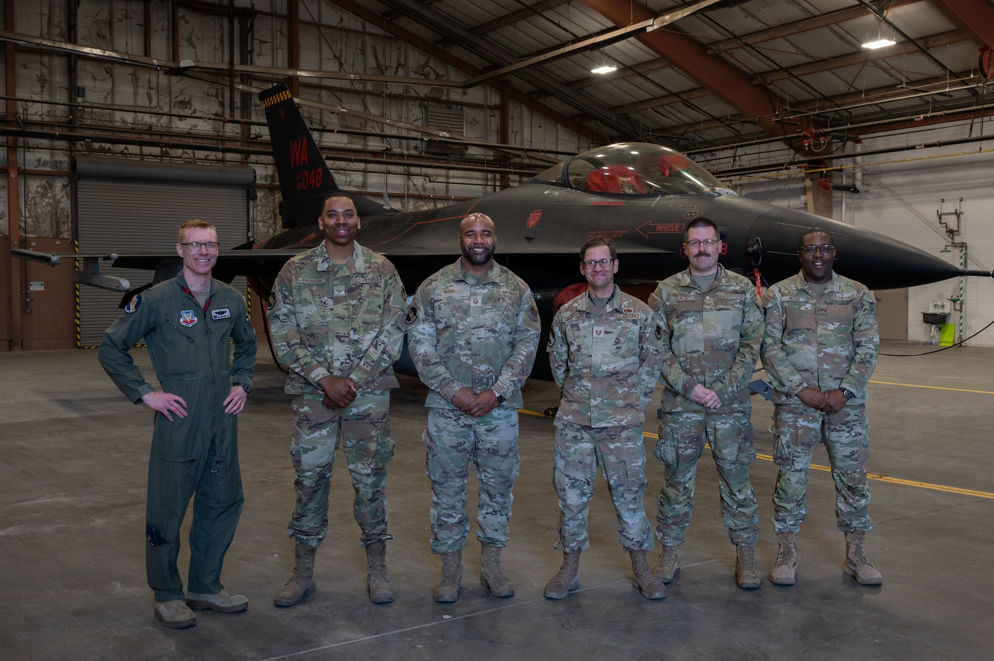 6 Airmen stand in front of an F-16