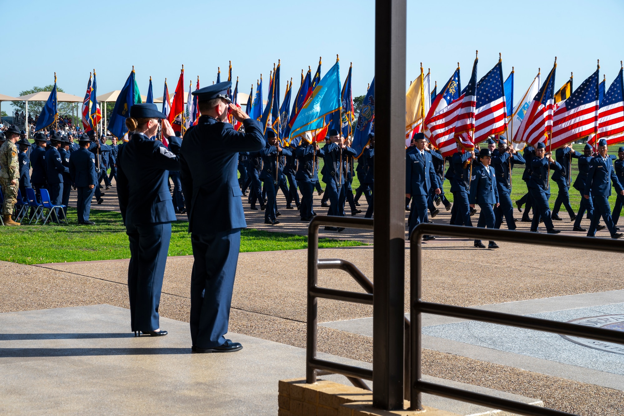 U.S. Air Force Col. Sergio Anaya, 62d Airlift Wing commander, and Chief Master Sgt. Kristy Korchak-Campbell, 62d AW command chief, salute the American flag during the Basic Military Training graduation parade pass in review at Joint Base San Antonio-Lackland, Texas, April 10, 2025.